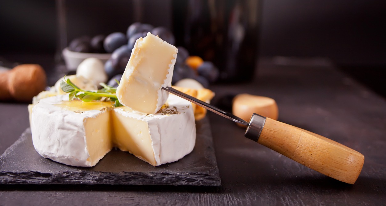 Cheese camembert brie on the board, two glasses and bottle of red wine