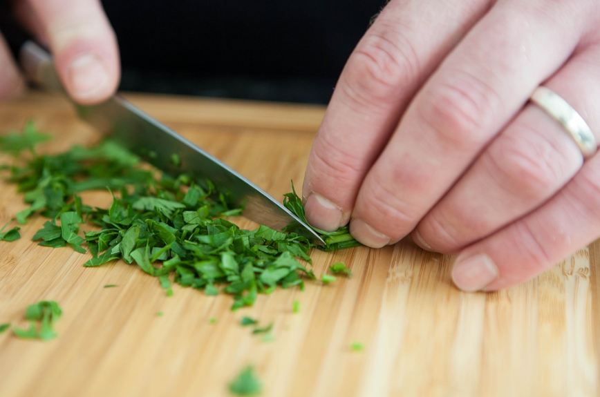a chef finely chopping herbs on a cutting board