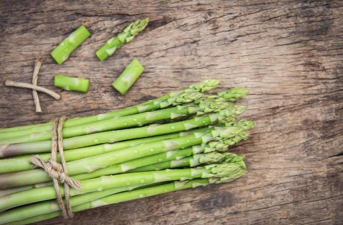 Image of a bunch of fresh asparagus on a wooden board.