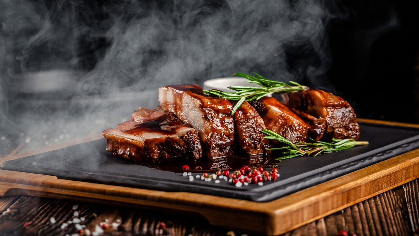 American food concept. Grilled pork ribs with grilled sauce, with smoke, spices and rosemary. Background image. copy space
