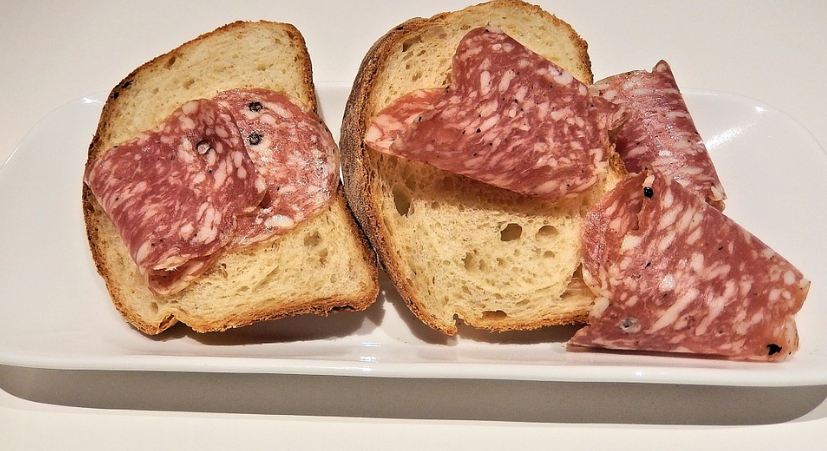bread and soppressata slices on a white plate