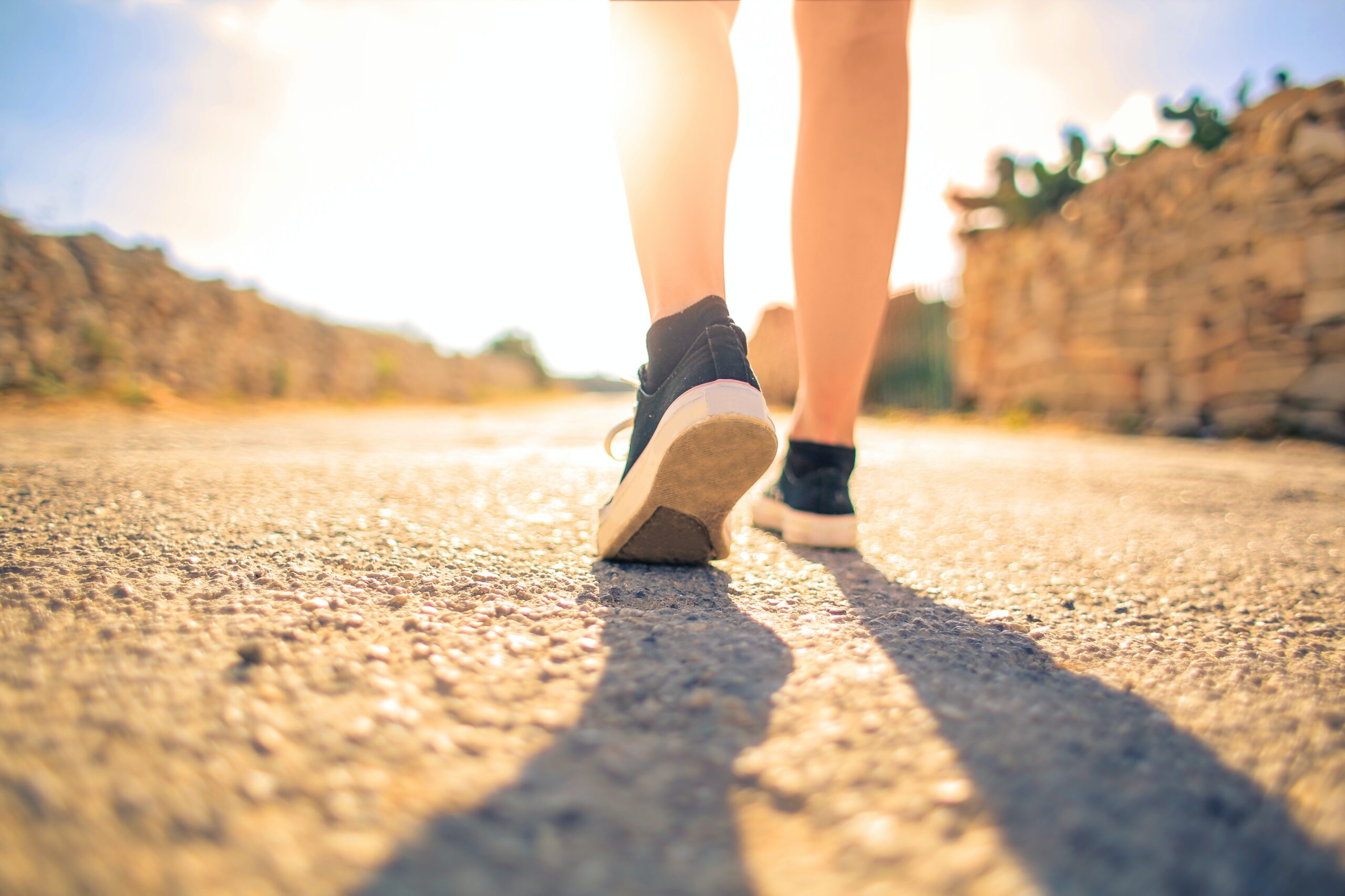 woman-walking-on-pathway-under-the-sun