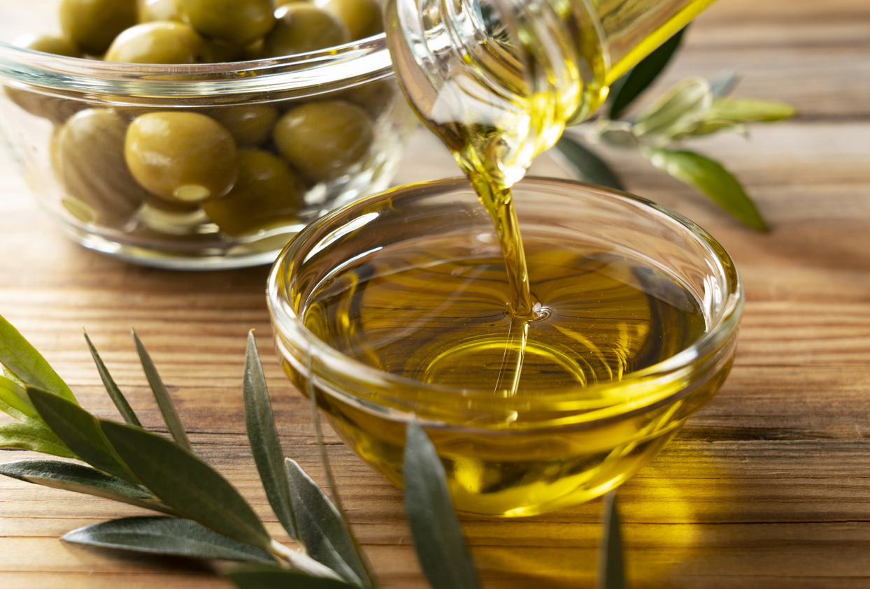Olive oil in a glass bowl set against a wooden background