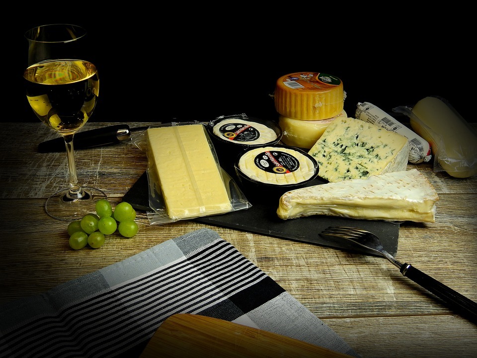 a glass of white wine paired with different cheeses