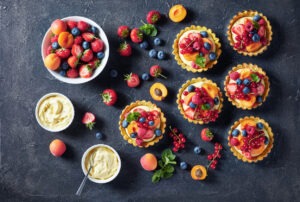 Summer tartlets with fresh custard creamy filling topped with raspberries, apricots, blueberry, strawberry, red currants