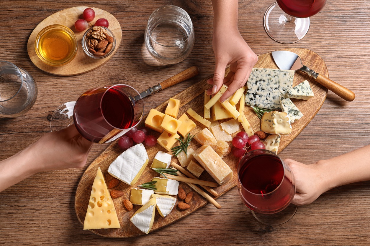Women with glasses of wine and cheese plate on table