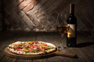 Italian pizza, bottle and glass of wine on wooden tabletop