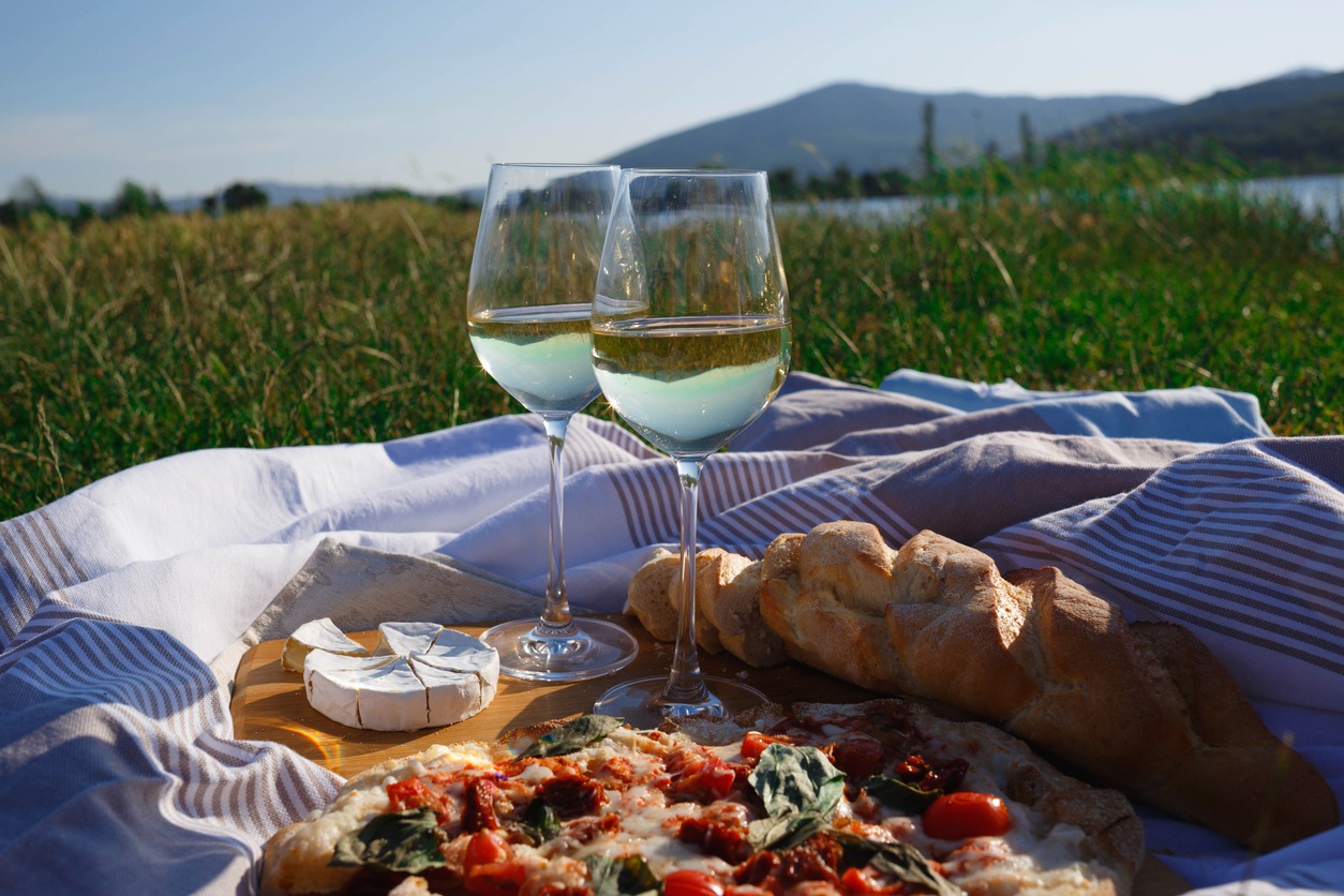Picnic in nature- pizza, cheese, baguette and glasses of wine