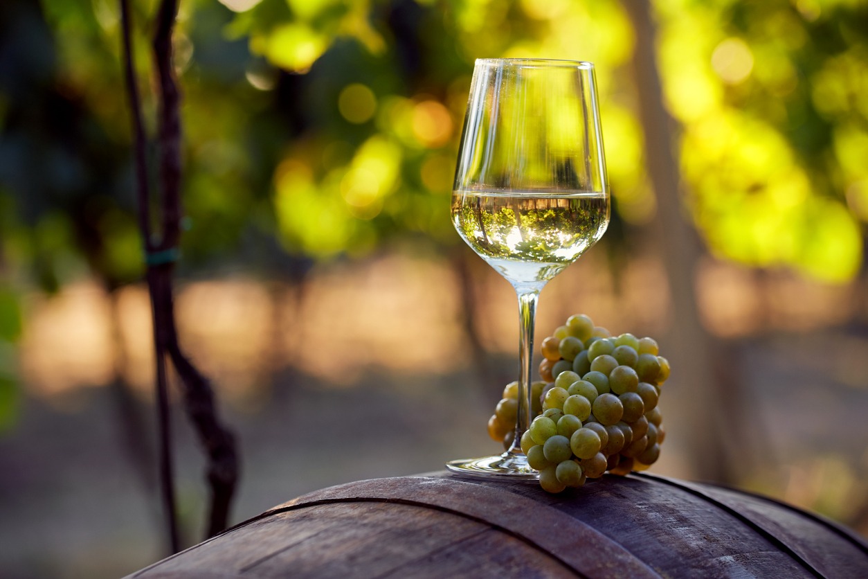White wine with grapes on a barrel