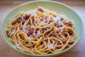Bowl of pasta all'amatriciana with grated parmesan cheese