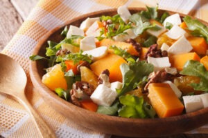 Healthy salad with persimmon, arugula and cheese close-up