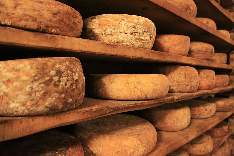 Italian cheeses on display on a wood rack
