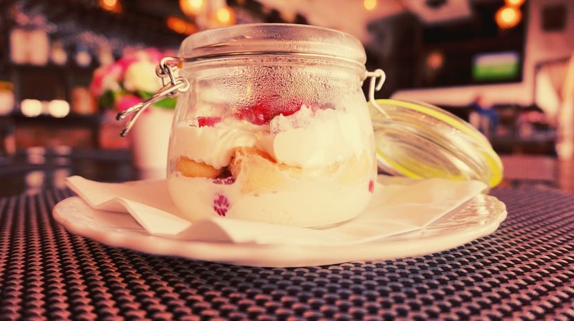strawberry tiramisu in a jar, jar on a plate, table, restaurant