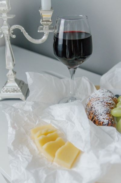 a glass of wine, candelabra, pastries, white cloth