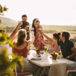 a group of people toasting wine during a dinner party outdoors
