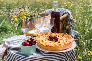 Table view served with beautiful vintage wine glasses, plates, silver cutlery and tableware, tablecloth, sweet cherry pie and fresh cherries still life. Homemade baking and recipes illustration.